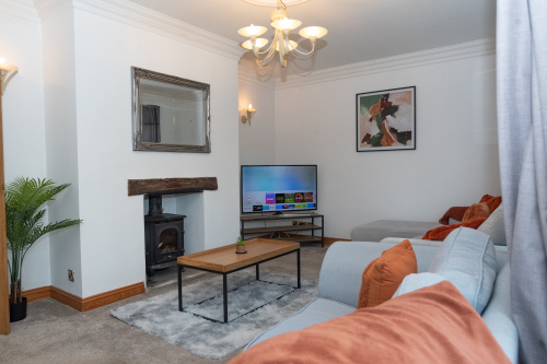 Comfortable lounge featuring generous seating, a smart 4K TV with apps, and a wood-burning stove for cosy nights spent together