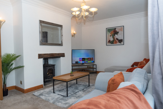 Comfortable lounge featuring generous seating, a smart 4K TV with apps, and a wood-burning stove for cosy nights spent together