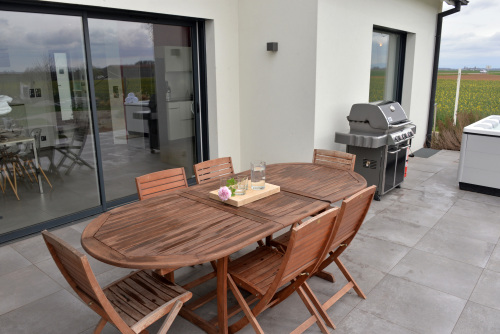 Grande terrasse avec mobilier de jardin et barbecue Weber