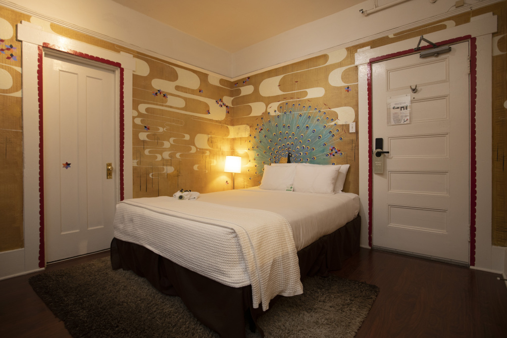 A hotel room with a bed, lamp, and decorative wall art