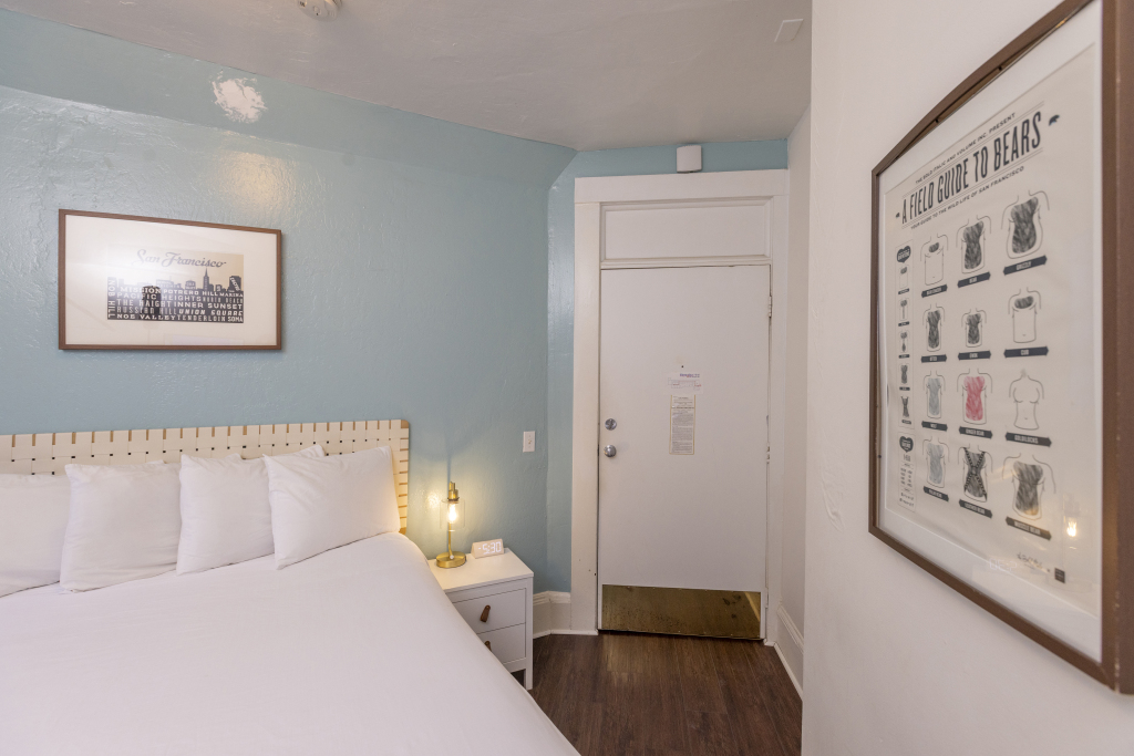 A hotel room with a bed, nightstand, and door