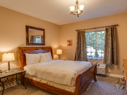 Rustic Chic Suite Bedroom with Pillowtop Queen Bed dressed in Luxurious Linens and Down Comforter. Bedroom also features a flatscreen television, alarm clock and closet.