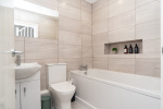 A bright, modern master bathroom featuring a full bathtub and complimentary essentials for a relaxing stay.