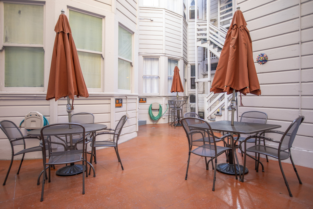 A small outdoor seating area with tables, chairs, and umbrellas in a courtyard