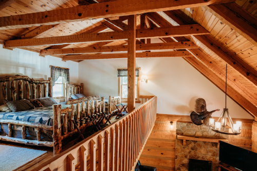 Upstairs loft area with king and twin size log beds overlooking the living room