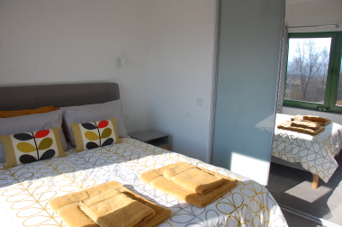 Bedroom with fluffy towels and large mirrored wardrobe.