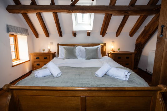 Light, bright upstairs bedroom with natural exposed beams, hotel-style fresh linens and soft towels