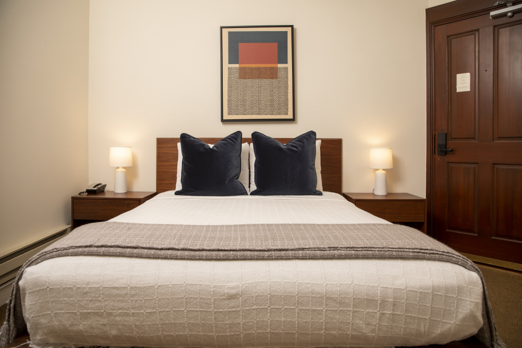 A neatly made bed with two nightstands and lamps in a hotel room.