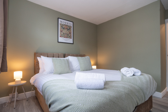 Relax in this serene green bedroom featuring soft olive accents, premium hotel-style bedding, and fresh towels each stay. The comfy king bed can be arranged as twins for total flexibility.