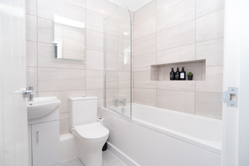 Spacious master bathroom with bath and shower, complete with complimentary shampoo, conditioner and shower gel for a comfortable, hotel-style stay.