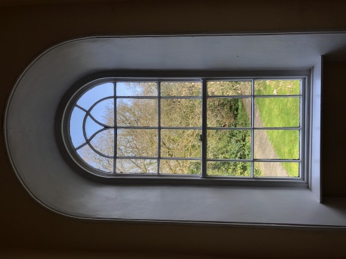The huge handblown glass window illuminates the grand staircase of the East Wing .