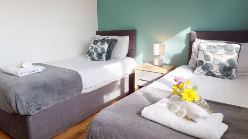 SRK Serviced Accommodation - Bedroom 2 with beautiful pastel colour feature wall. Bedside lamp and wardrobe.