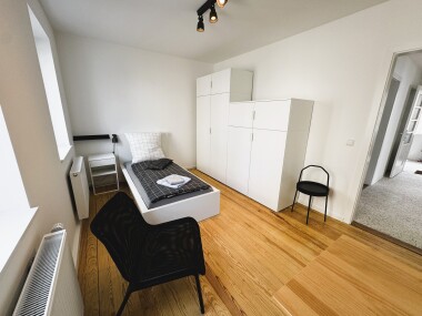 Einzelzimmer mit Fenster, Stuhl und modernem Ambiente