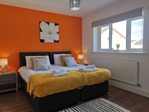 SRK Serviced Accommodation - Master bedroom with bedside lamp and wardrobe, large window and ensuite.
