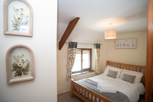 Characterful Double Bedroom - Exposed barn beam, botanical pressed-flower artwork and crisp hotel-quality linens with fresh towels on arrival, ideal for a proper Devon retreat.