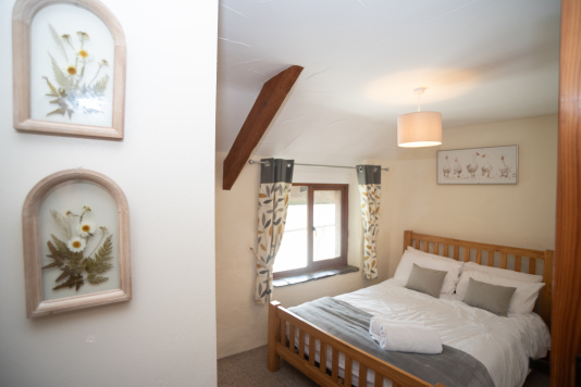 Characterful Double Bedroom - Exposed barn beam, botanical pressed-flower artwork and crisp hotel-quality linens with fresh towels on arrival, ideal for a proper Devon retreat.