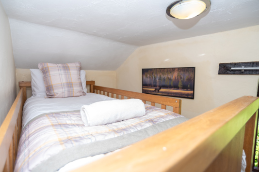 The upper bunk offers a cosy sleeping nook, perfect for younger guests seeking their own holiday hideaway.