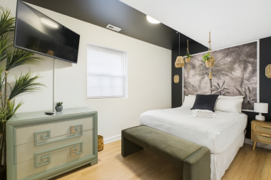 Enjoy the comfort of a queen-sized bed surrounded by earthy textures and calming tones. Tropical mural, natural wood touches, and woven pendant lights create a boutique-hotel feel.