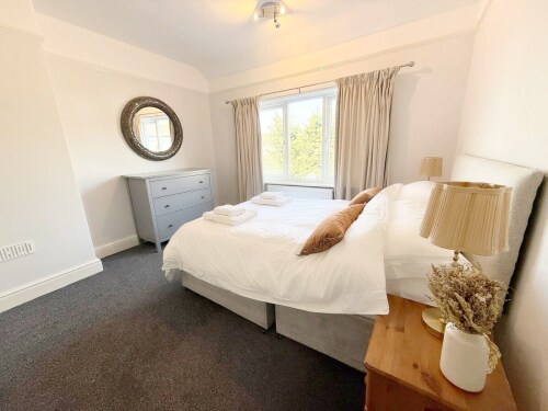 Bedroom Two is a charming double bedroom at the rear of the property with a memory foam-topped mattress. It features a large mirror, hanging area, chest of drawers, and two nightstands with lamps. Ideal for a couple or children.