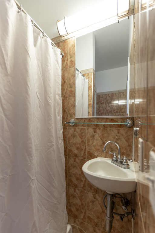A bathroom with a shower curtain, sink, and mirror.