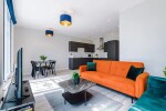A spacious living room with a large TV, cosy sofas, and a fully equipped kitchen, ideal for relaxing and unwinding after a day of exploring.