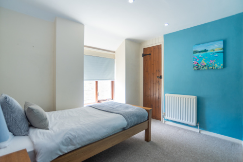 Soft teal tones and coastal artwork make this Single room feel like a proper Devon retreat