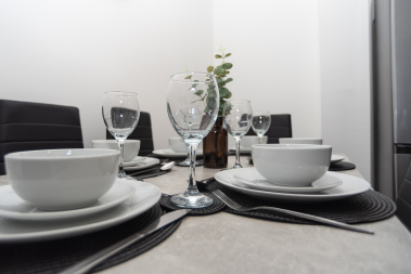 Dining table fully set with everything you need for a home-cooked meal — plates, cutlery and cookware ready for relaxed, family-style or team dining.