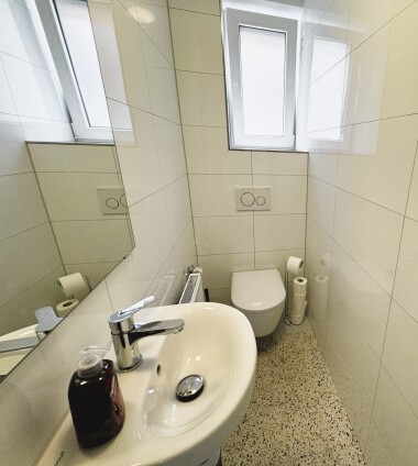 Separate Toilette mit Waschbecken und Tageslichtfenster