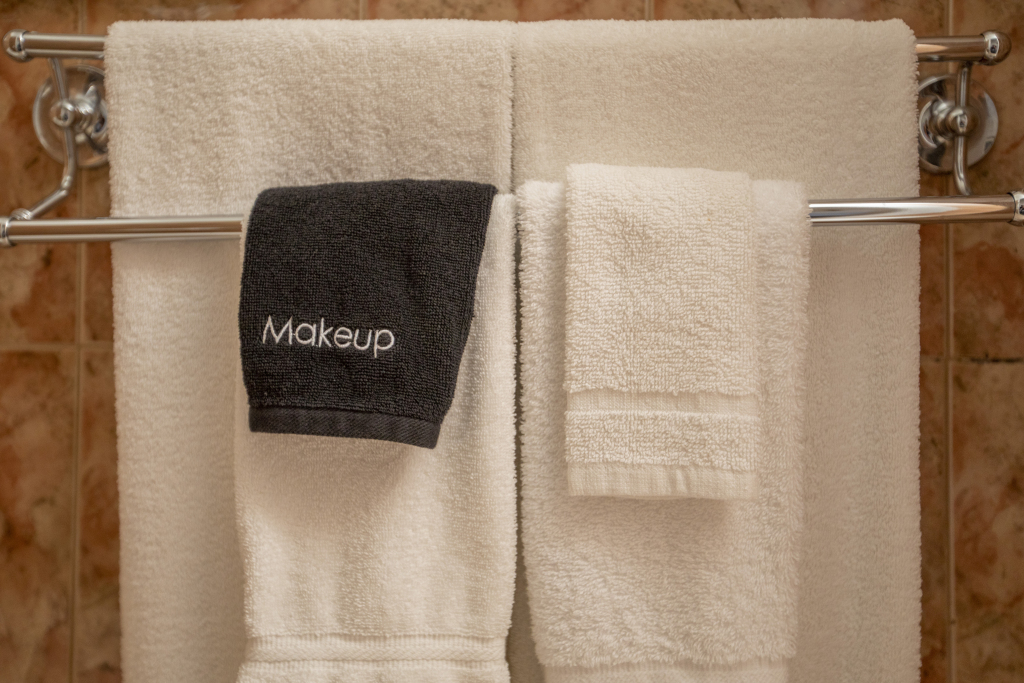 A close-up of towels and a makeup cloth hanging on a rack in a bathroom.