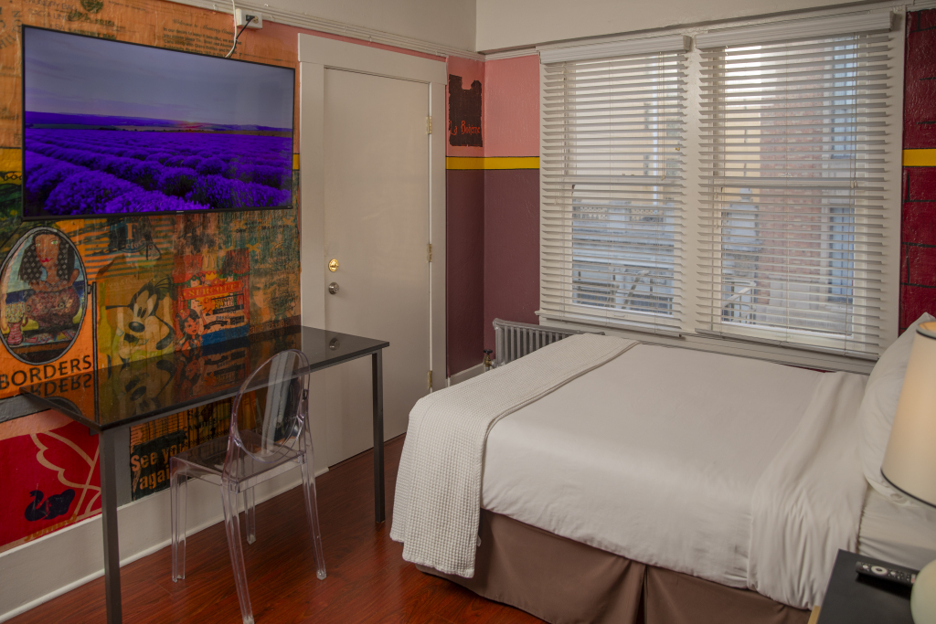 A hotel room with a bed, desk, and TV