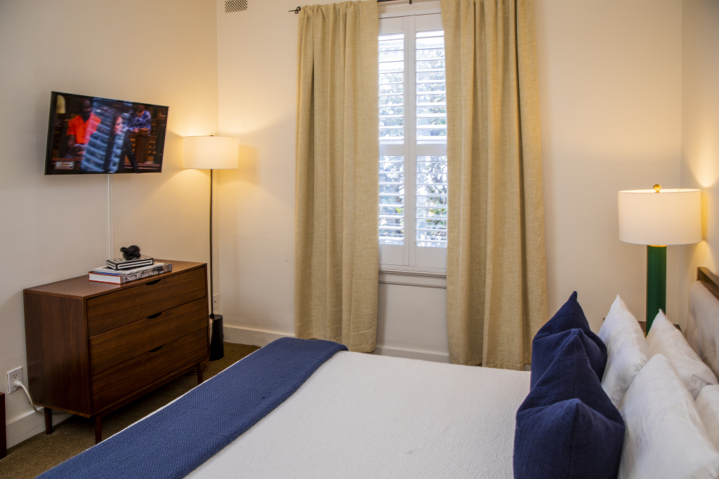 A neatly arranged hotel room with a bed, TV, dresser, and lamps.