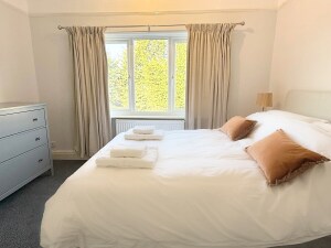 Bedroom Two is a charming double bedroom at the rear of the property with a memory foam-topped mattress. It features a large mirror, hanging area, chest of drawers, and two nightstands with lamps. Ideal for a couple or children.