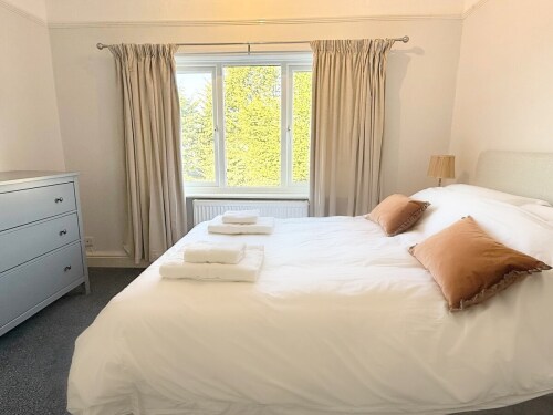 Bedroom Two is a charming double bedroom at the rear of the property with a memory foam-topped mattress. It features a large mirror, hanging area, chest of drawers, and two nightstands with lamps. Ideal for a couple or children.