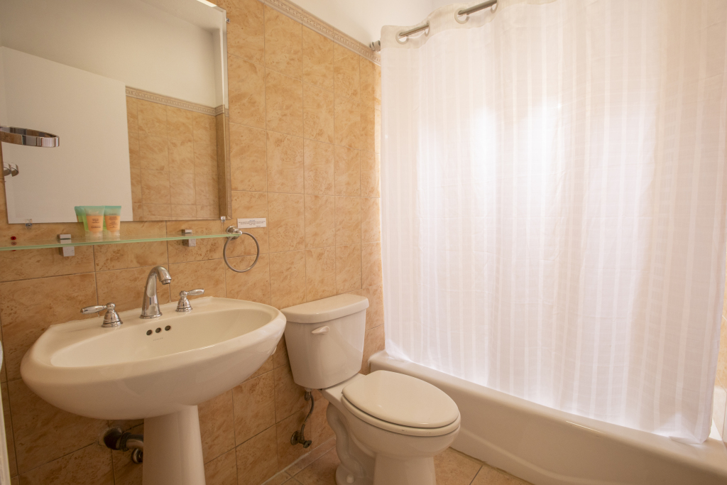 A bathroom with a toilet, sink, bathtub, and mirror