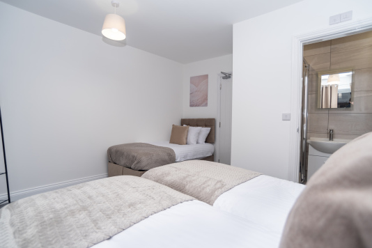 Master bedroom with zip-link beds that convert from two singles into a king, complete with private en suite — offering ultimate flexibility for any group