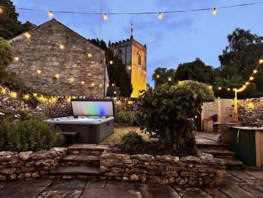Stunning private garden featuring a luxury hot tub and soft romantic lighting, perfectly positioned to soak up peaceful views of the beautiful village church in Kettlewell.

An idyllic setting for evening drinks under the stars, slow mornings with a coffee in hand, or unwinding after a day exploring the Dales - your own secluded sanctuary with a truly special backdrop.