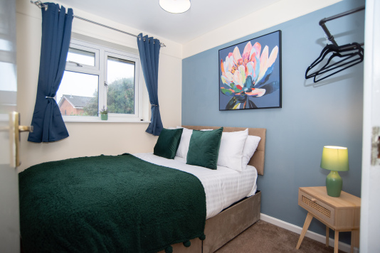 A comfortable third bedroom with a double bed and clothing rail, finished with hotel-quality linens and towels provided for your stay.