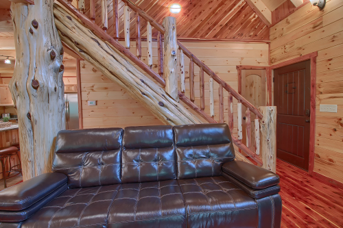 Couch, Cedar log stairs to Loft Level, and Front Entrance, from Great Room