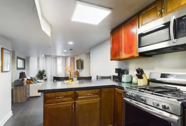 Whip up your favorite meals in this kitchen, featuring stainless steel appliances, a gas stove, a microwave, & ample counter space. The open layout connects seamlessly to the living area, creating a cozy & functional space for dining and relaxing.