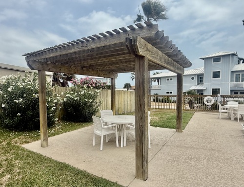 Shared dining area at pool shaded by pergola