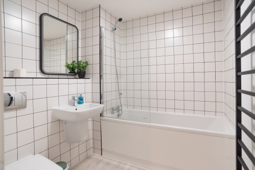 Modern bathroom with bath and overhead shower, perfect for relaxing after a day exploring Folkestone