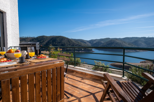 Balcony over the lake with outdoor furniture, barbecue and large awning.