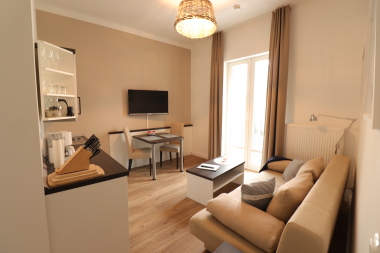 Wohnzimmer mit hochwertiger Schlafcouch, TV, Esstisch und Küchenzeile