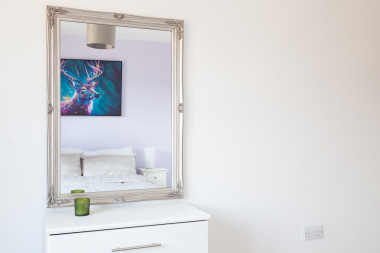 2nd bedroom, AKA 'The Purple Room' features some ontracting purple canvas art and a large mirror for a homelike feel. 