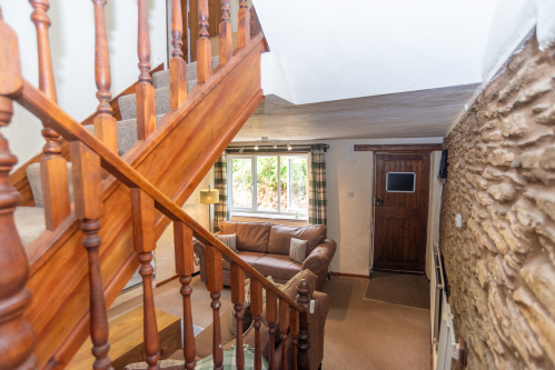 Overlooking the cosy lounge, this view highlights the cottage's traditional stone walls and welcoming open-plan layout.