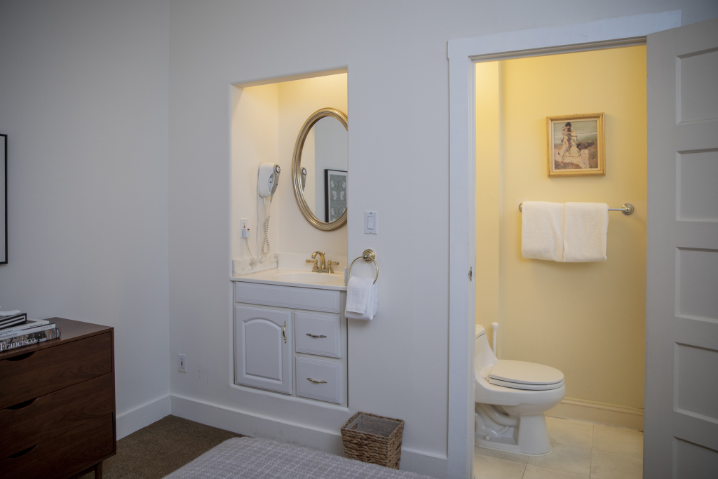 A bathroom with a white sink, mirror, towels, and toilet
