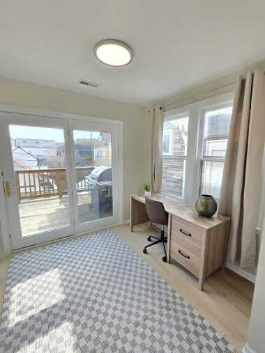 This bright office space offers a peaceful environment for work or study, featuring a modern desk, comfortable chair, and ample natural light. The sliding doors provide access to the outdoors, creating an inspiring workspace.