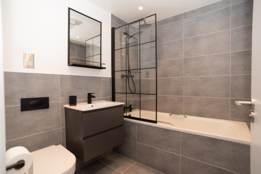 A spacious master bathroom with bath and shower, one of two bathrooms in the apartment, complete with shampoo, conditioner and shower gel for a comfortable stay with family, colleagues or friends.