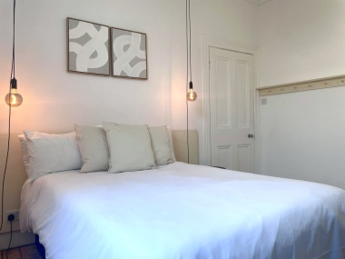 Spacious double bedroom with crisp white linen and stylish pendant lighting