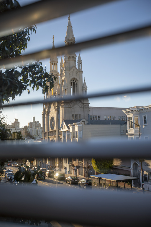 A view of a church and city street through blinds